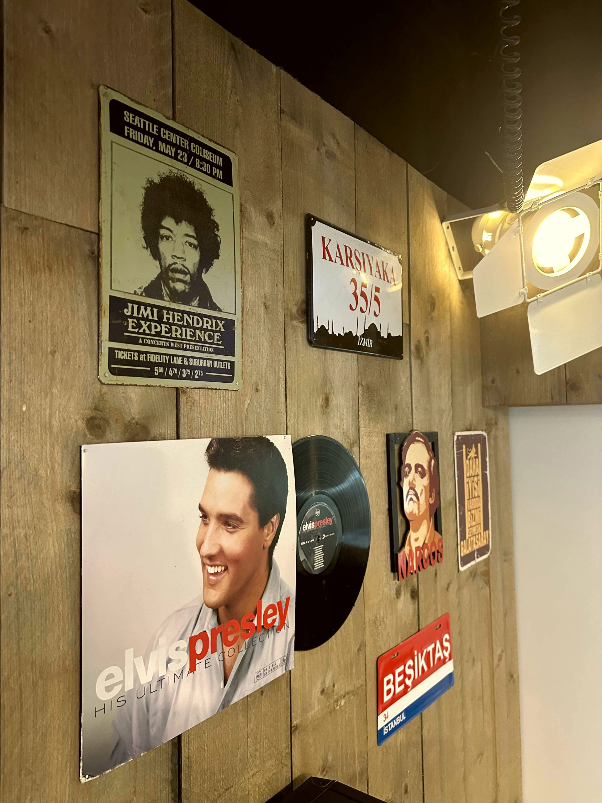 Wand met posters en Turkse memorabilia in Estria Barbershop